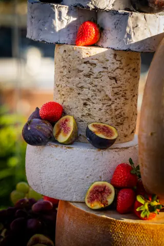 Stacked cheese wheel tower topped with strawberries and figs