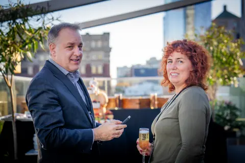 Two attendees talking on the rooftop terrace with the Montreal skyline behind them