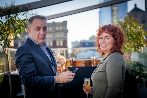Two guests chatting with drinks on the rooftop at the ElevateOS multifamily networking event