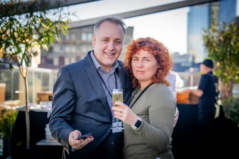 Two attendees smiling with champagne on the rooftop terrace