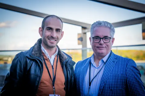 Two multifamily professionals with event lanyards smiling on the rooftop