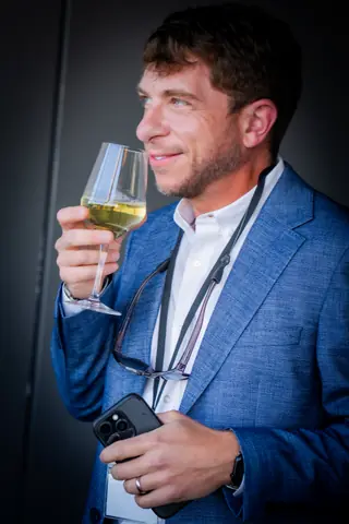 Guest in a blue blazer holding a glass of white wine on the terrace