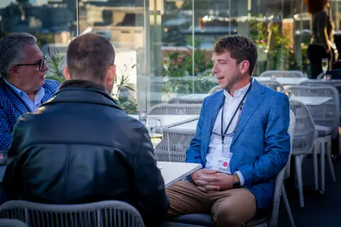 Four attendees in conversation at a table on the rooftop