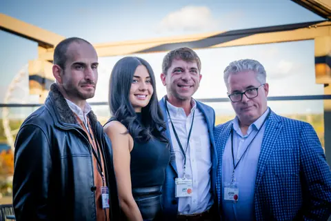 Four attendees posing together on the rooftop at the ElevateOS networking event