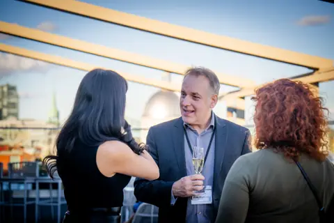 Three guests in conversation with drinks on the terrace