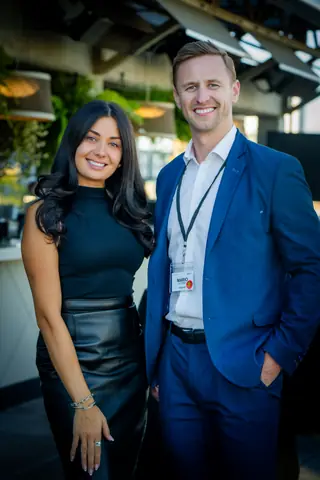 Two attendees posing together near the rooftop bar