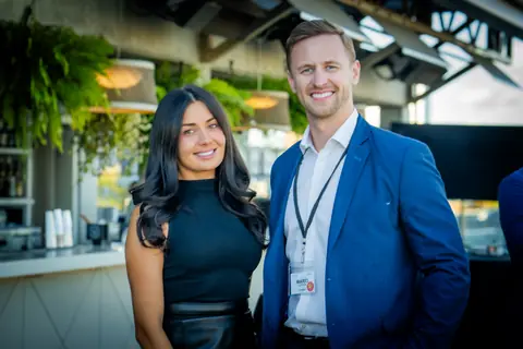 Two guests with event lanyards smiling by the bar