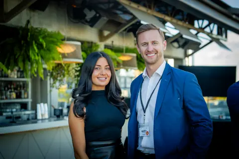Two attendees photographed together by the rooftop bar