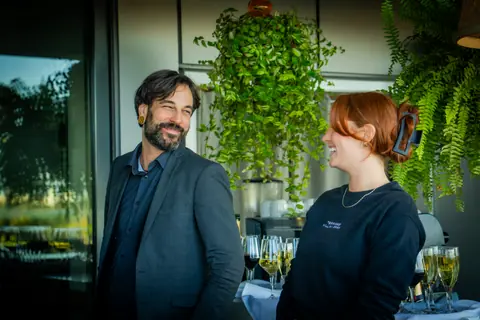 Attendee talking with event staff beside a tray of champagne glasses