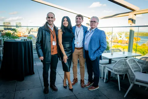 Group of four attendees posing on the rooftop with the Old Port behind them