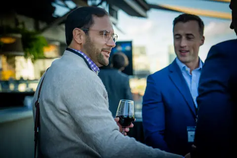 Attendees in conversation, one holding a glass of red wine