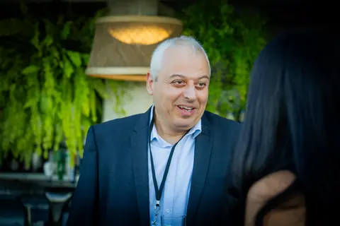 Attendee with an event lanyard smiling in conversation by the bar