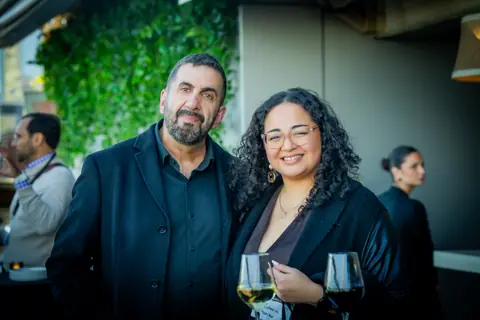 Two attendees smiling with glasses of white wine