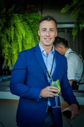 Smiling attendee in a blue blazer holding a cocktail