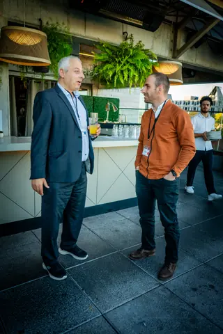 Two attendees in conversation by the bar