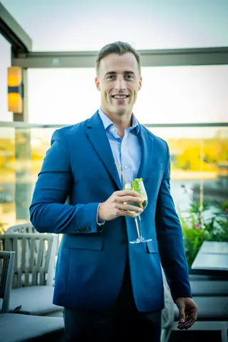 Attendee in a blue blazer holding a cocktail on the terrace
