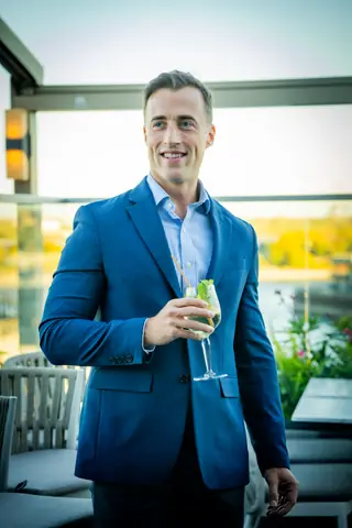 Guest smiling with a cocktail at golden hour