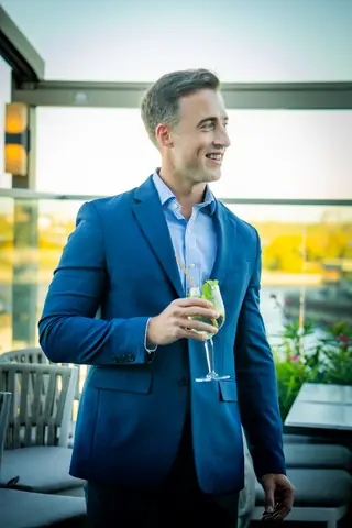 Attendee in a blue blazer with a drink on the rooftop