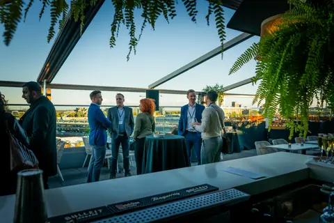 Guests mingling along the rooftop bar as the sun sets