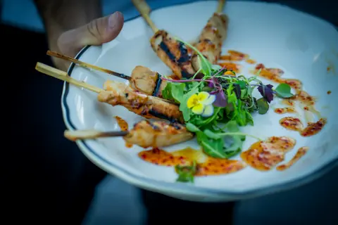 Plate of grilled chicken skewers with a herb salad