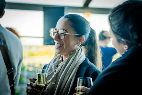 Two attendees laughing with glasses of champagne