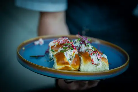 Mini lobster rolls served on a blue plate