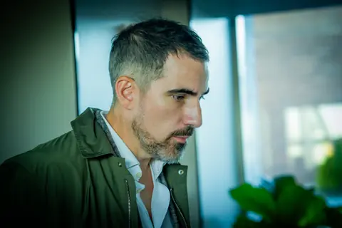 Attendee in a green jacket in a quiet moment by the window