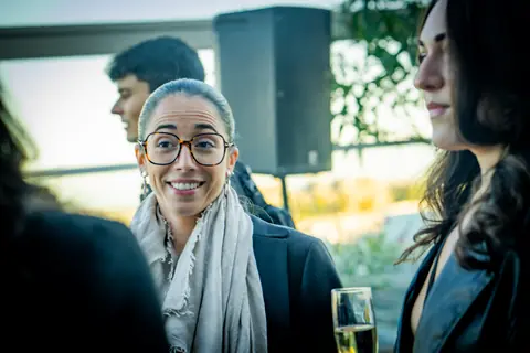 Smiling attendee in glasses talking with other guests