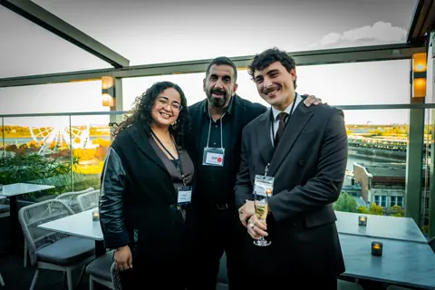 Three attendees posing together on the rooftop with the Old Port behind them