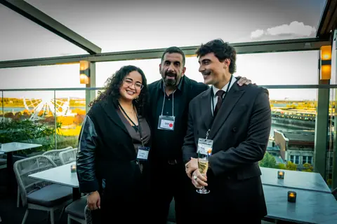 Three guests with event lanyards smiling on the terrace