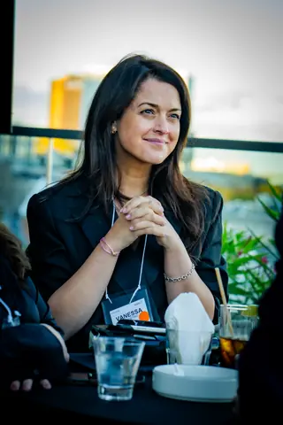 Smiling attendee seated at a terrace table