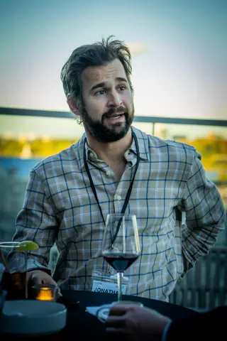 Attendee in a plaid shirt with a glass of red wine