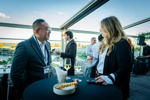 Attendees gathered around a high table on the rooftop