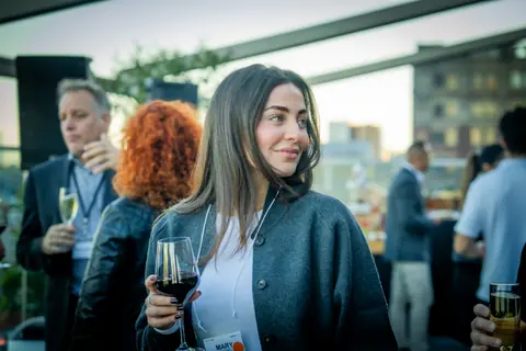 Attendee holding a glass of red wine among guests on the terrace