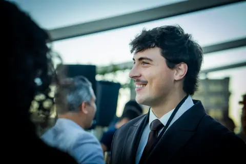 Attendee in a suit smiling during a conversation at sunset