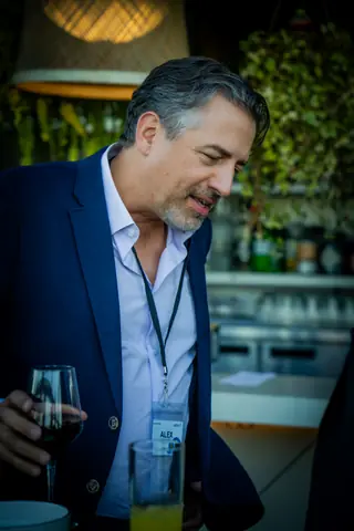 Attendee with a glass of white wine by the bar