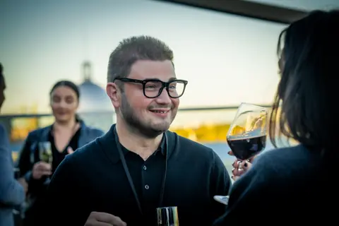 Attendee in glasses smiling with a glass of red wine on the terrace