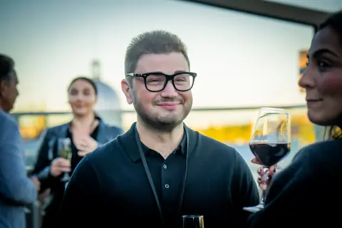 Guest in glasses laughing during a conversation at golden hour