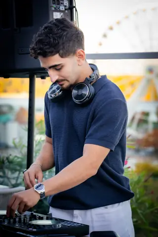 DJ at the decks with the Old Port Ferris wheel behind him