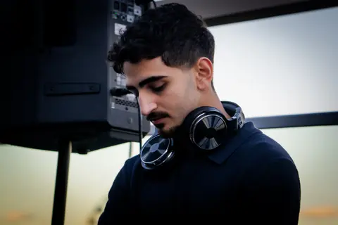 DJ with headphones around his neck at the rooftop set