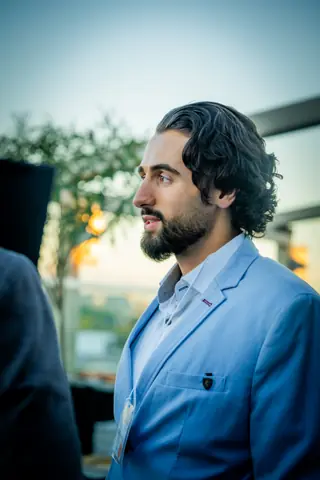 Attendee in a light blue blazer listening on the terrace