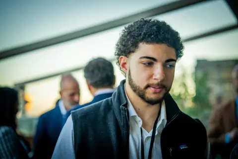 Guest in a vest listening during a conversation on the rooftop