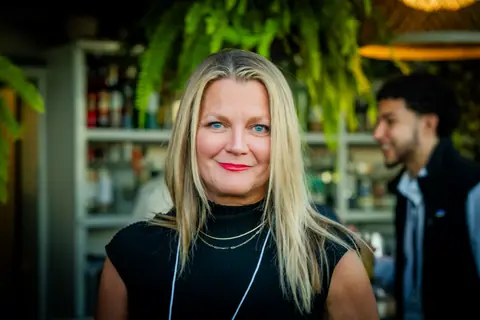 Smiling attendee with an event lanyard by the rooftop bar