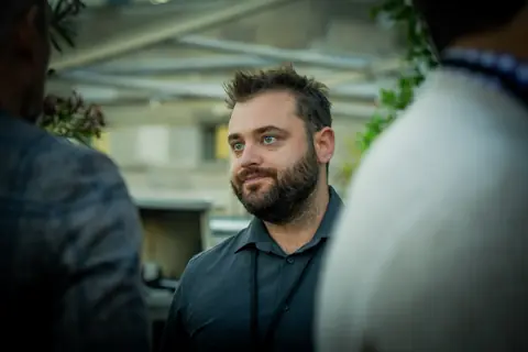Attendee in a dark shirt listening to another guest