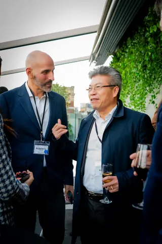 Two attendees with event badges talking on the rooftop