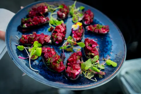 Beet tartare canapés with microgreens on a blue plate