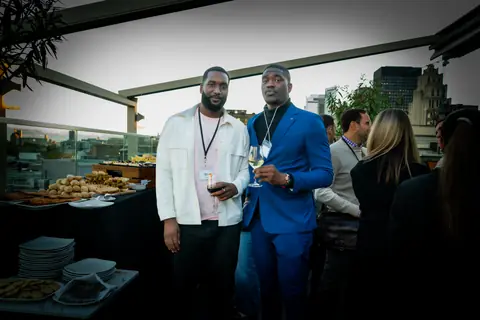 Two attendees talking by the buffet on the rooftop terrace