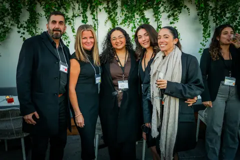 Group of attendees posing together by the ivy wall at the ElevateOS Montreal event