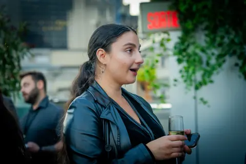 Attendee with a glass of white wine talking with guests on the terrace