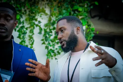 Two attendees in an animated conversation by the ivy wall